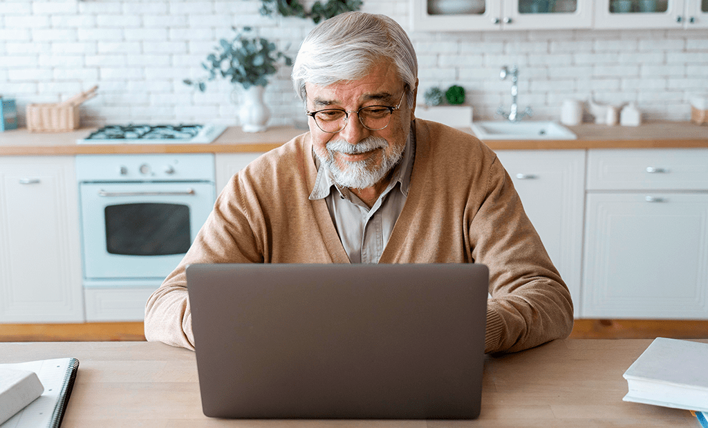 #descricaodaimagem #pratodosverem foto de um homem idoso usando um notebook.