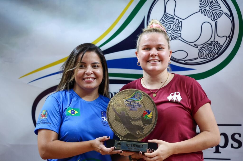 #descricaodaimagem #pracegover foto de Giselle Pereira entregando o troféu de melhor goleira