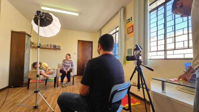 #descricaodaimagem #pratodosverem foto de uma entrevista para o café-escola inclusivo. Um homem está de costas e, à sua frente, estão uma criança e uma mulher.