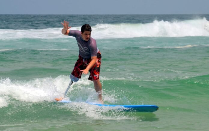 foto de um rapaz surfando. Ele usa uma prótese de perna direita.
