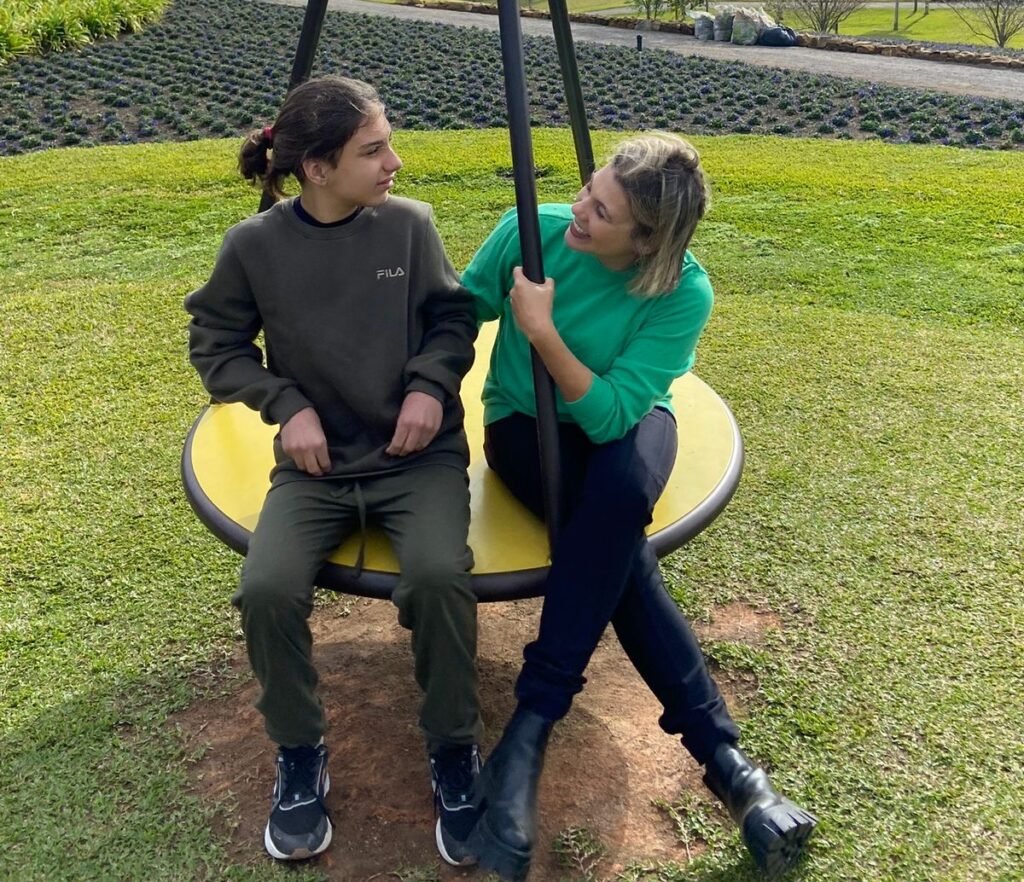 #descriçãodaimagem #pratodosverem foto de Pedrinho com sua mãe. Eles estão sentados num balanço.
