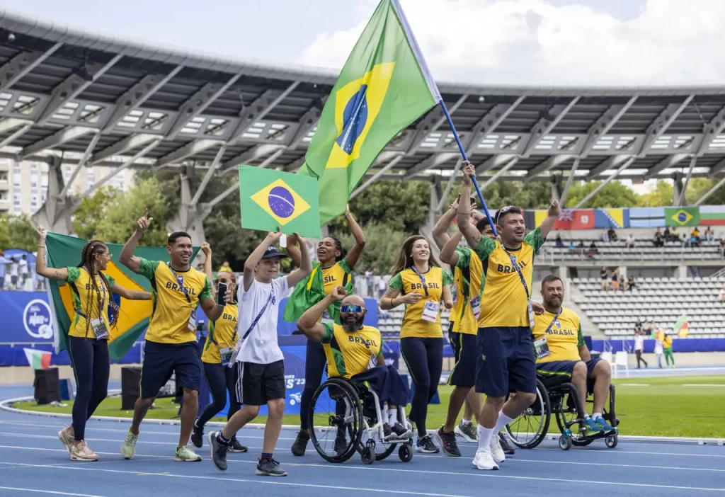 #descriçãodaimagem #pratodosverem foto da seleção brasileira de atletismo em Paris, com o velocista Petrúcio Ferreira carregando a bandeira.