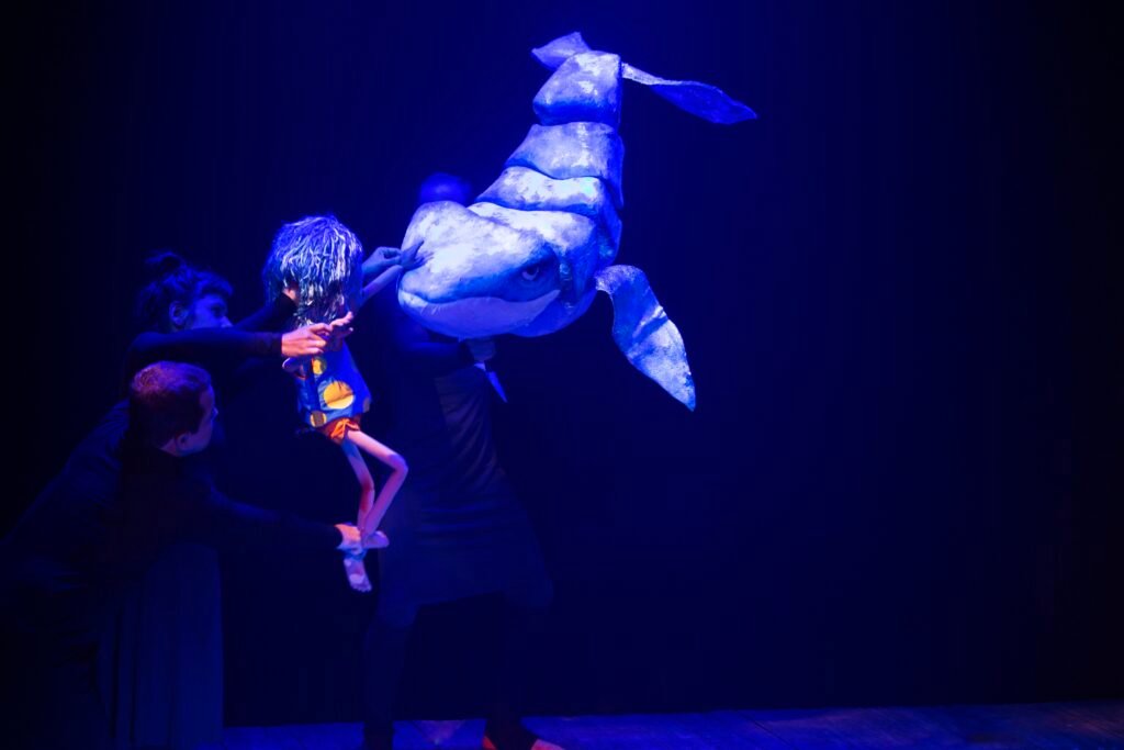 #descriçãodaimagem #pratodosverem cena do espetáculo 'Azul'. Pessoas estão manipulando o personagem e uma baleira.