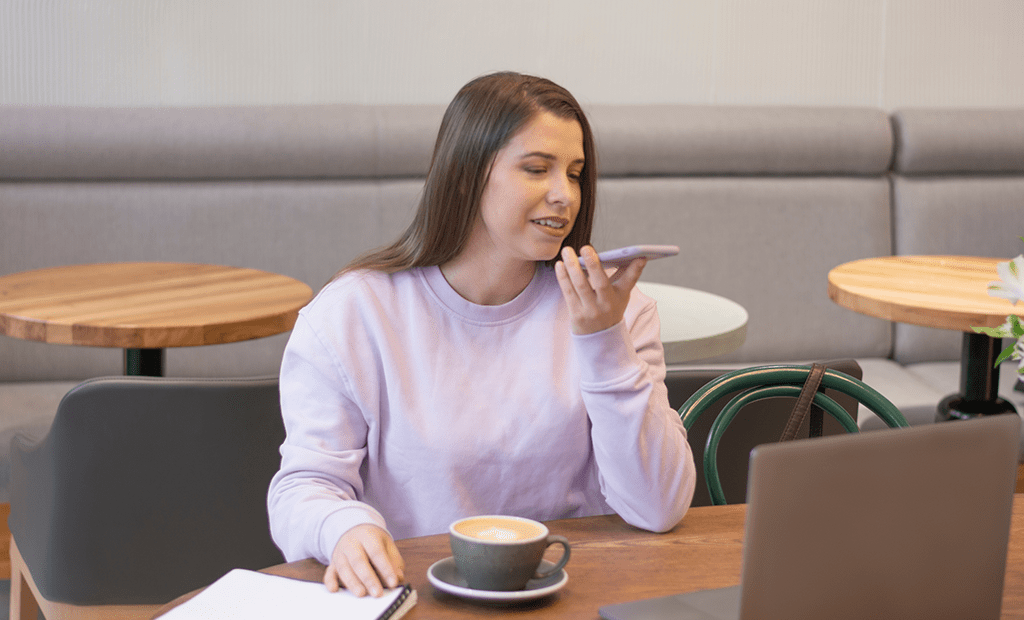 #descriçãodaimagem #pratodosverem foto de uma mulher branca. Ela está vestindo um moletom, tem cabelos longos e está falando no telefone e tomando café.