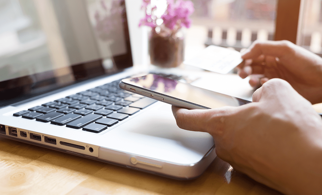 #descriçãodaimagem #pratodosverem foto de um notebook aberto e uma mão segurando um cartão e um celular.